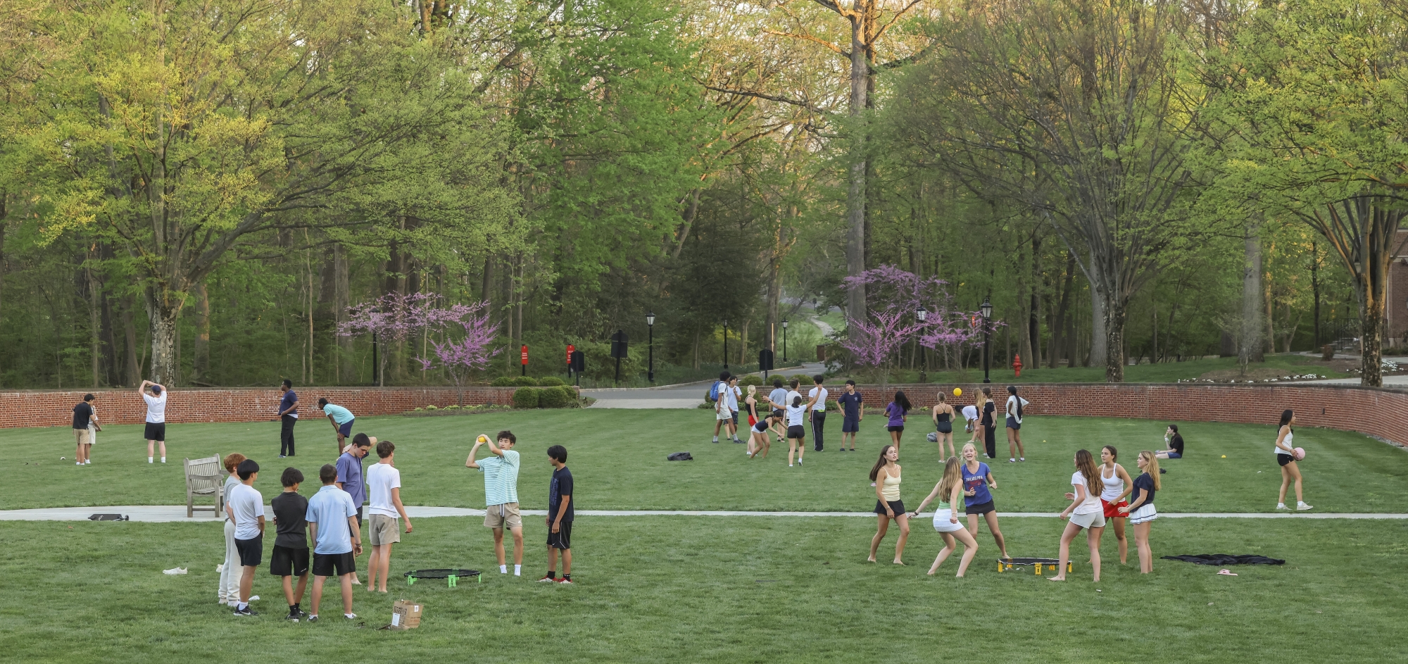 At twilight, young students gather on the grass to play games and socialize.